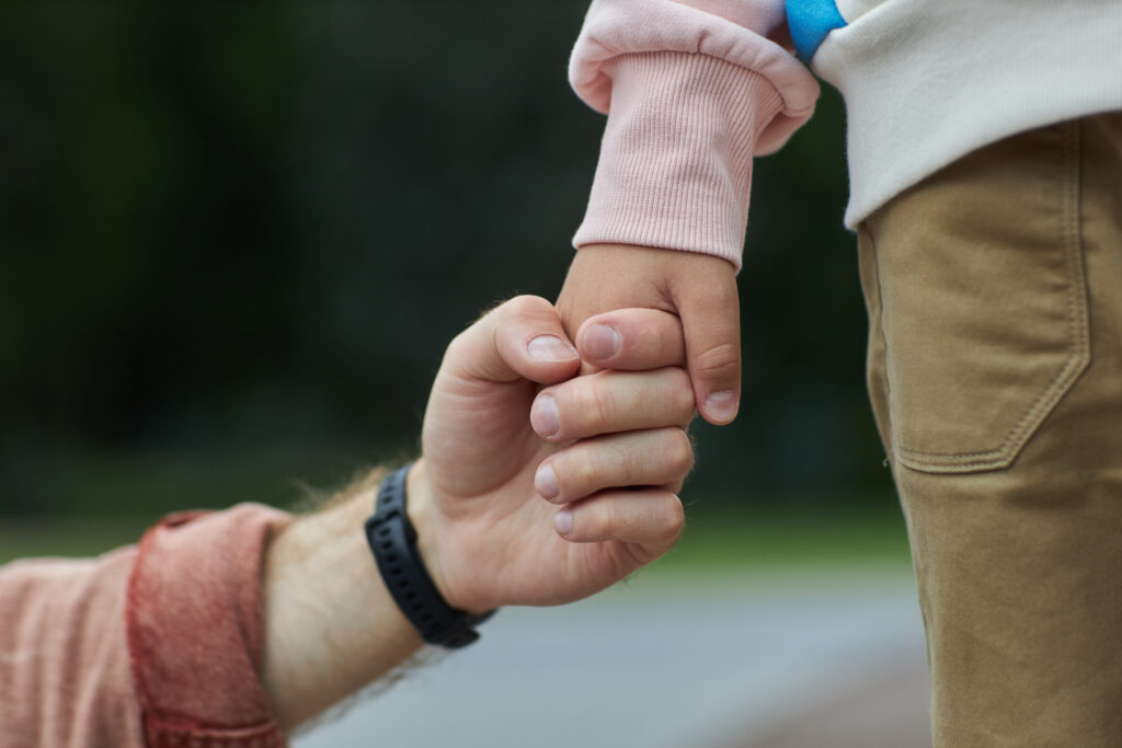 Father holding hands with his little boy outdoors, symbolizing family relationships and custody matters under Family Code 3044.