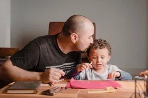 Father showing affection to child while reviewing financial documents, representing California child support where both parents share financial responsibility to provide for a child’s living expenses and well-being.